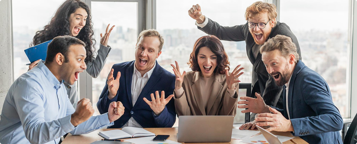 Happy team celebrating around laptop